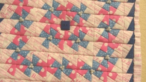 A mini quilt with pearls and buttons.